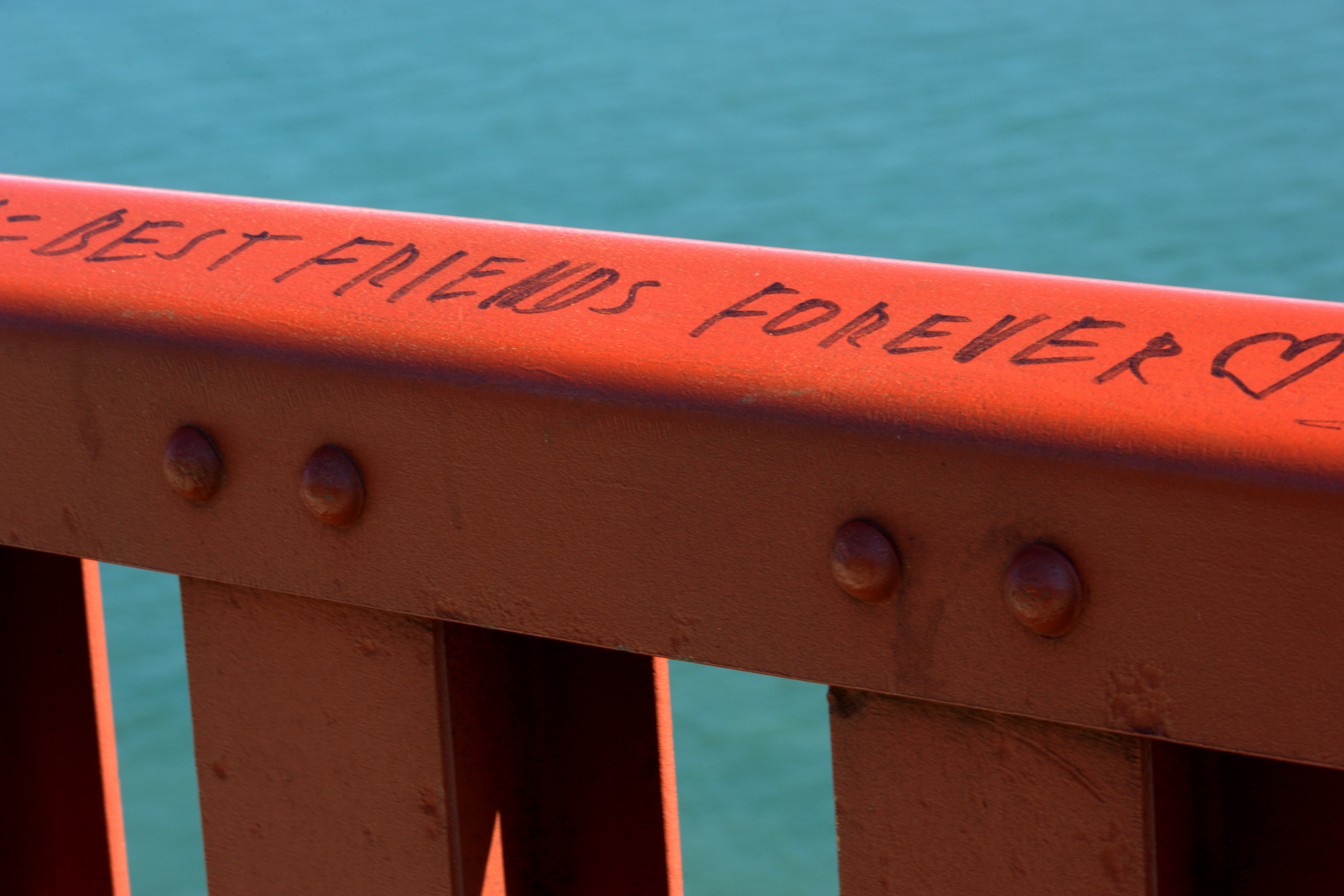 Guard rail along the east sidewalk of the Golden Gate Bridge in San Francisco, California. A permanent marker inscription reads "Best friends forever ?".